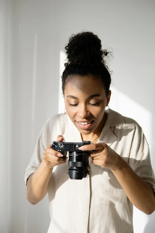 a woman taking a picture with a camera, holding controller, photo of a black woman, looking down on the camera, product introduction photos