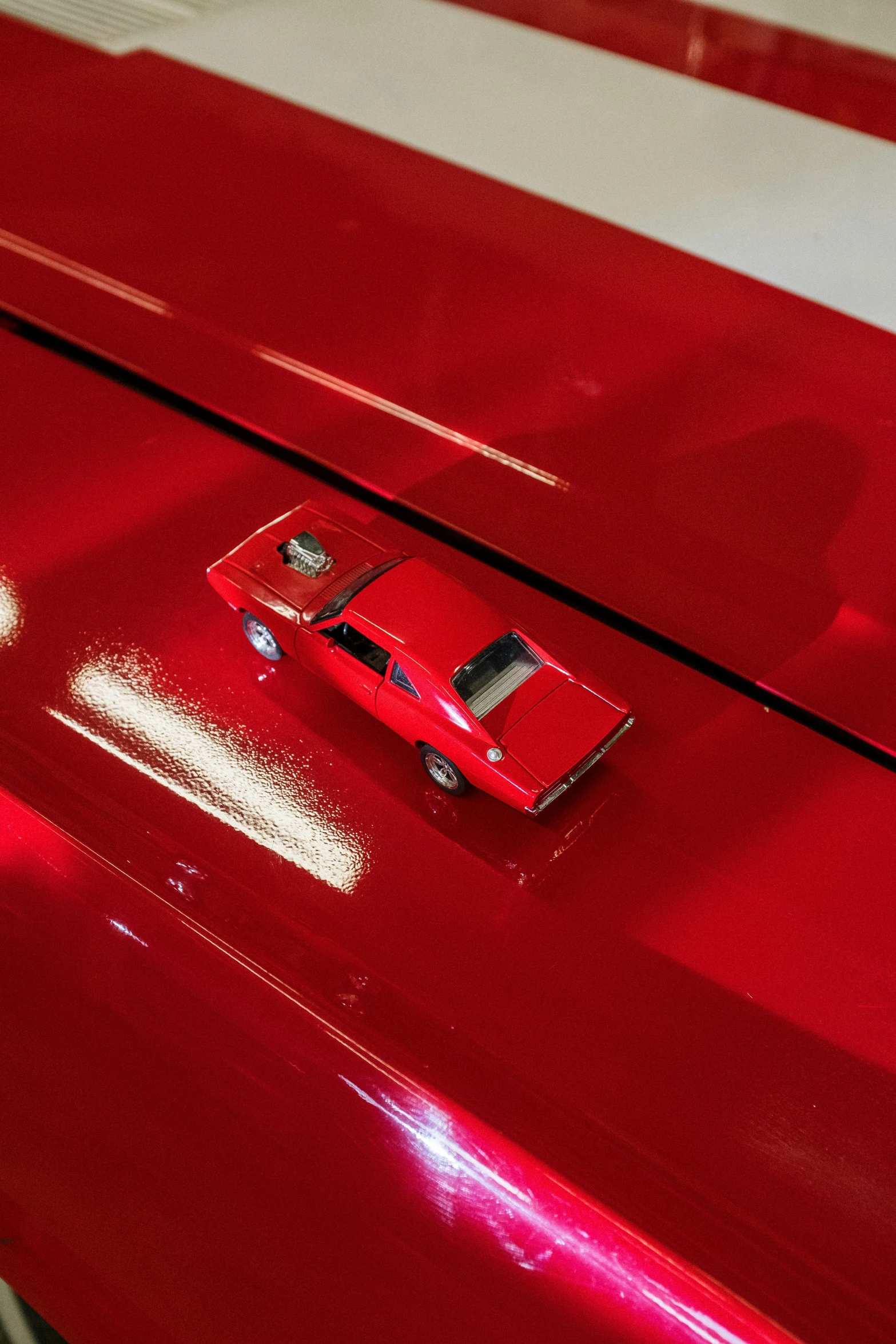 a toy car sitting on top of a red car, an airbrush painting, by Tom Bonson, pexels contest winner, detail shot, high gloss, high angle shot, 1 9 7 9