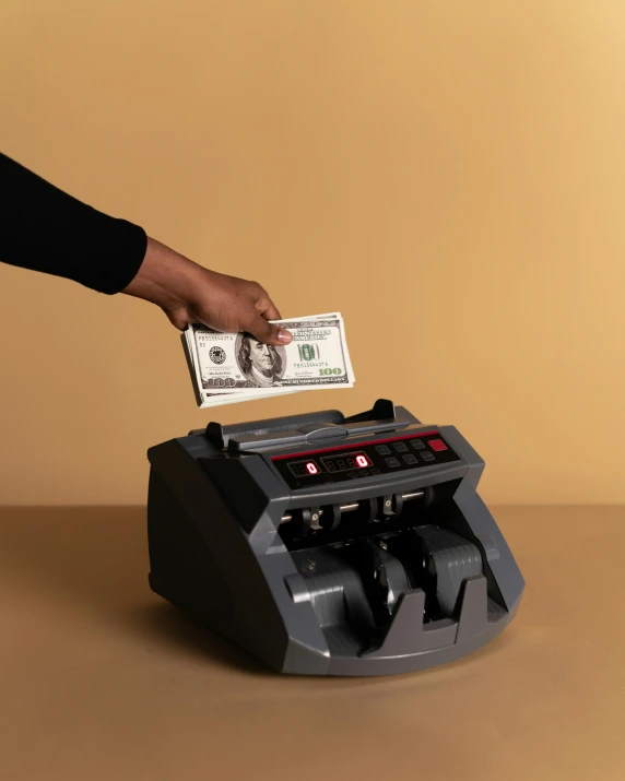 a person putting money into a counting machine, an album cover, by Julia Pishtar, pexels contest winner, brown, plain background, 15081959 21121991 01012000 4k, 10k