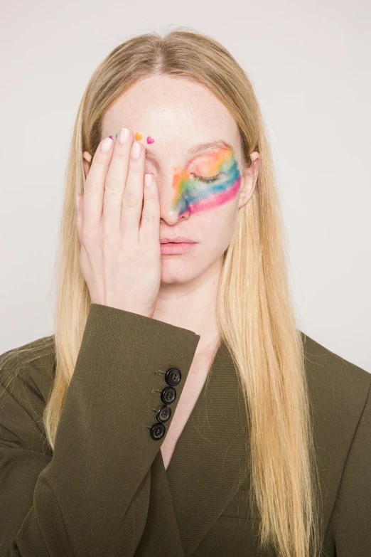 a woman with a painted face covering her eyes, an album cover, trending on pexels, rainbow, britt marling style, margiela campaign, facepalm