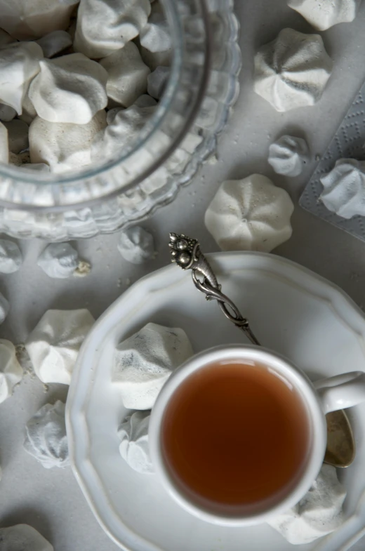 a cup of tea sitting on top of a saucer, a still life, inspired by Perle Fine, trending on unsplash, baroque, marshmallows, close up of single sugar crystal, sculpted, photograph from above