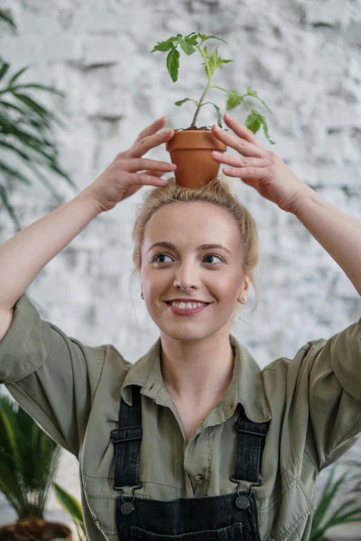 a woman holding a potted plant above her head, pexels contest winner, smiling slightly, avatar image, tending on pinterest, taller than man