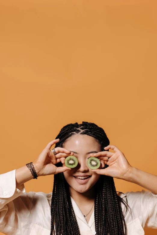 a woman holding two slices of kiwi in front of her eyes, trending on pexels, mixed-race woman, minimalist photo, ilustration, louise zhang