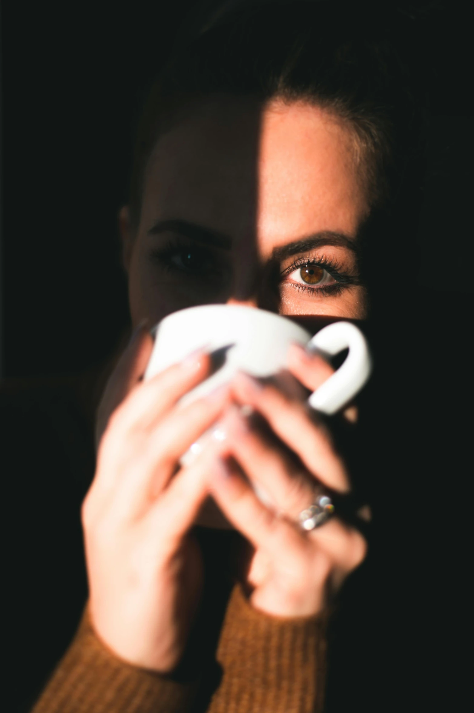 a woman holding a video game controller in front of her face, inspired by Elsa Bleda, pexels contest winner, minimalism, with a white mug, dark angel of coffee, her face is in shadow, high contrast portra 400