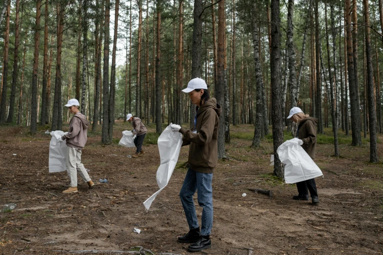 a group of people walking through a forest, by Attila Meszlenyi, unsplash, process art, bags on ground, cleaning future, in russia, maintenance photo