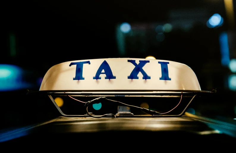 a close up of a taxi sign on top of a car, by Matija Jama, trending on unsplash, happening, avatar image, night photo, 1 9 8 0 s photo, sitting down