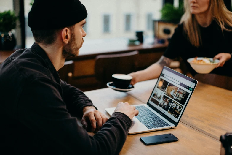 a man and a woman sitting at a table with a laptop, trending on pexels, award winning webdesign, 9 9 designs, kacper niepokolczycki, sitting in a cafe alone