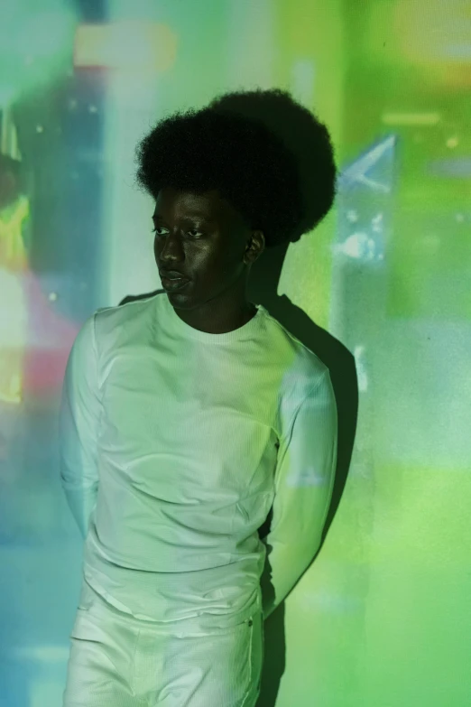 a man that is standing in front of a wall, an album cover, pexels, afrofuturism, pale green glow, black man with afro hair, concert photo, iridescence