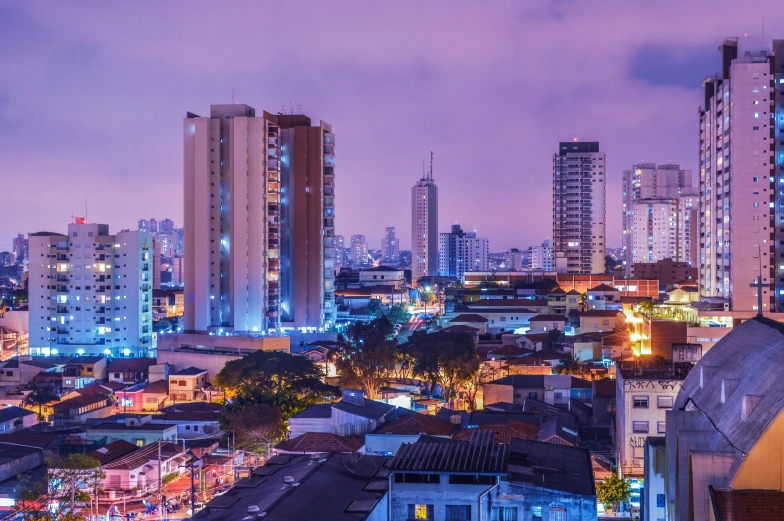 an aerial view of a city at night, by Emanuel Witz, pexels contest winner, graffiti, brazil, purple roofs, tall buildings in background, panoramic