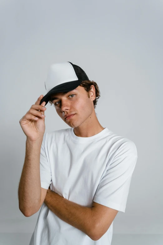 a young man wearing a white t - shirt and a black hat, unsplash contest winner, renaissance, gradient white to silver, trucker hat, frontal pose, no - text no - logo