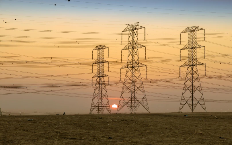 a group of power lines with the sun setting in the background, by Dan Luvisi, pexels contest winner, renaissance, desert sunrise in the background, stacks, central california, in a sunset haze