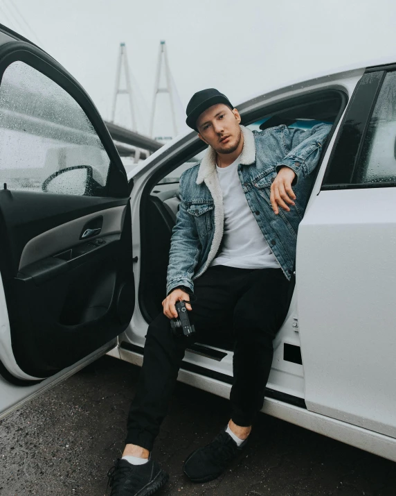 a man sitting in the open door of a car, pexels contest winner, lyco art, non binary model, casual pose, low quality photo, official product photo