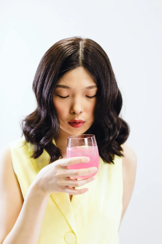 a woman holding a glass of pink liquid, by Eizan Kikukawa, pexels, gemma chan, 🍸🍋, lemonade, multiple stories