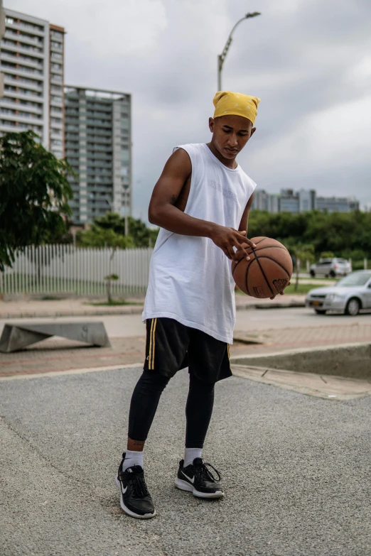 a man standing on a basketball court holding a basketball, trending on dribble, in sao paulo, baggy clothing and hat, white long tanktop, ( ( theatrical ) )