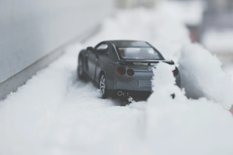 a toy car that is sitting in the snow, a tilt shift photo, pexels contest winner, photorealism, nissan gtr r 3 4, stealthy, 2019 trending photo, overcast! cinematic focus