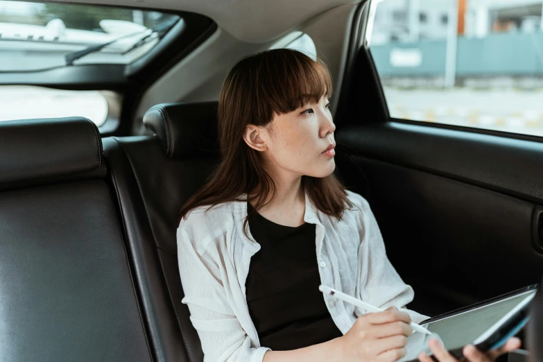 a woman sitting in the back seat of a car holding a tablet, pexels contest winner, happening, kotegawa yui, wearing business casual dress, profile image, thumbnail