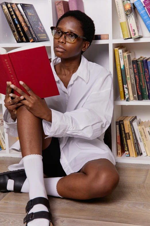 a woman sitting on the floor reading a book, by Nina Hamnett, trending on pexels, renaissance, portrait androgynous girl, nerdy black girl super hero, wearing red shorts, in a flowing white tailcoat