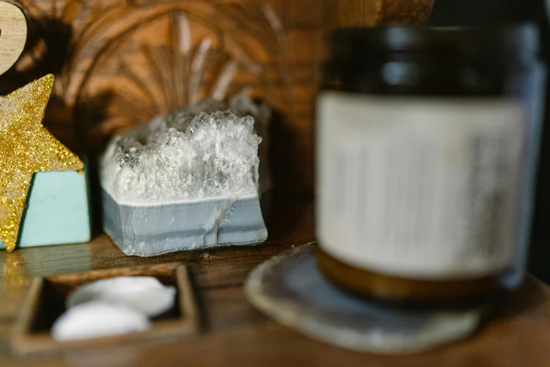 a candle sitting on top of a wooden table, a marble sculpture, by Helen Stevenson, unsplash, carved soap, jar on a shelf, close up of single sugar crystal, prussian blue
