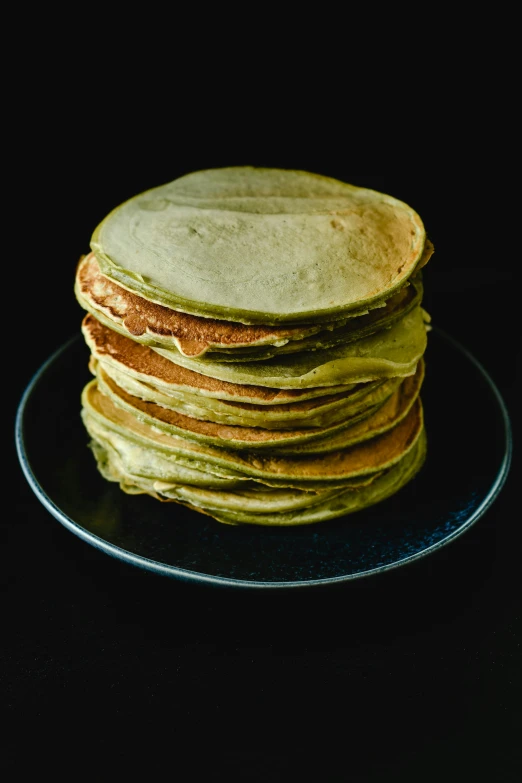 a stack of pancakes sitting on top of a black plate, by Winona Nelson, sage green, high - resolution scan, folded, portrait photo