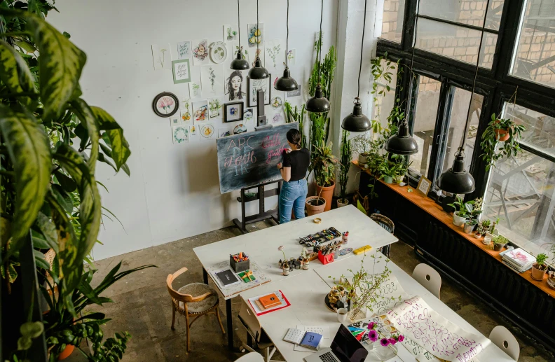 a person sitting at a table with a laptop, pexels contest winner, arbeitsrat für kunst, room full of plants, industrial space, hight decorated, standing on a desk