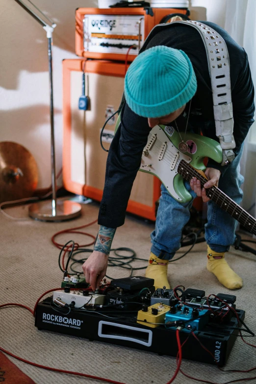 a man that is playing a guitar in a room, wearing teal beanie, electronics, lachlan bailey, instagram picture