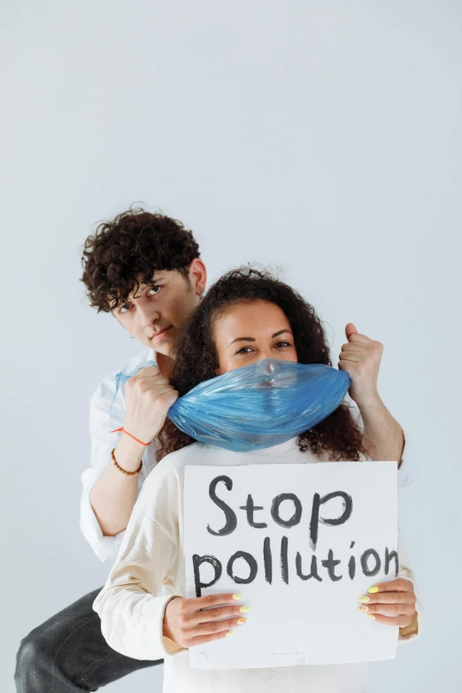 a man and woman holding a sign that says stop pollution, an album cover, by Matija Jama, trending on pexels, dust mask, profile picture, college, poop