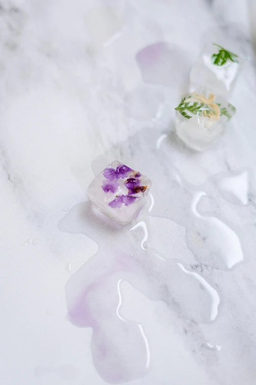 a group of ice cubes sitting on top of a marble counter, a watercolor painting, inspired by Daniel Gelon, trending on pexels, made of dried flowers, white and purple, made of ice, white