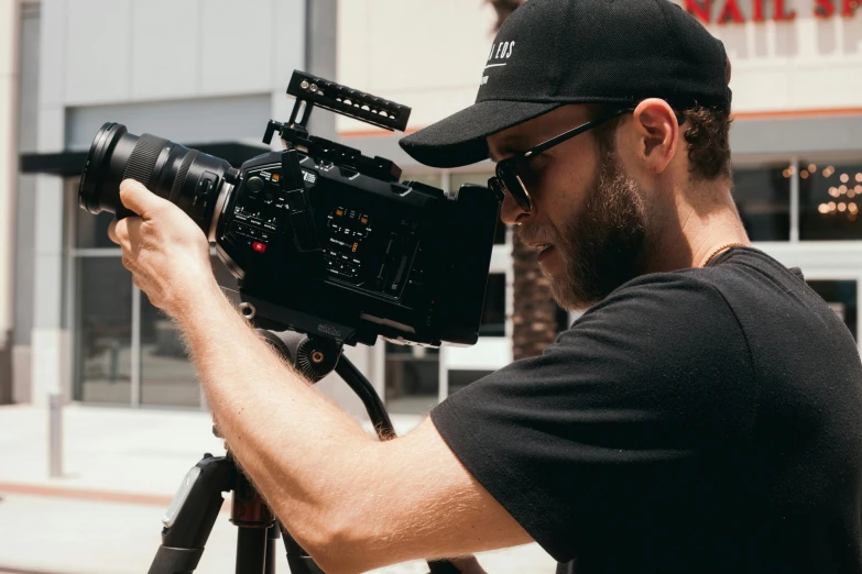 a man standing next to a camera on a tripod, pexels contest winner, video art, screenwriter, headshot, ultra realistic cinematic, over his shoulder