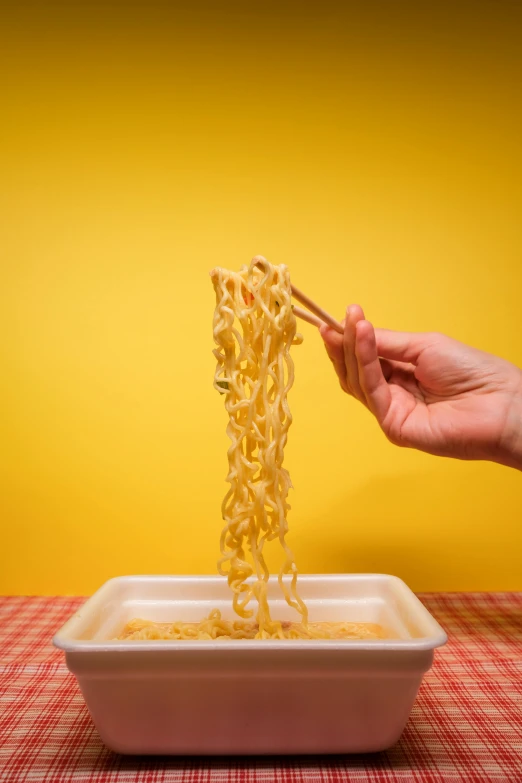 a person holding chopsticks over a bowl of noodles, realism, memphis, square, ap news photo, yellow