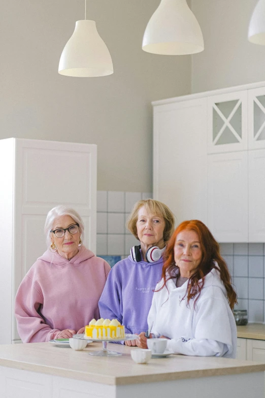 a group of women standing next to each other in a kitchen, inspired by Sigrid Hjertén, 7 0 years old, wearing a hoodie and flowers, stålenhag, cake