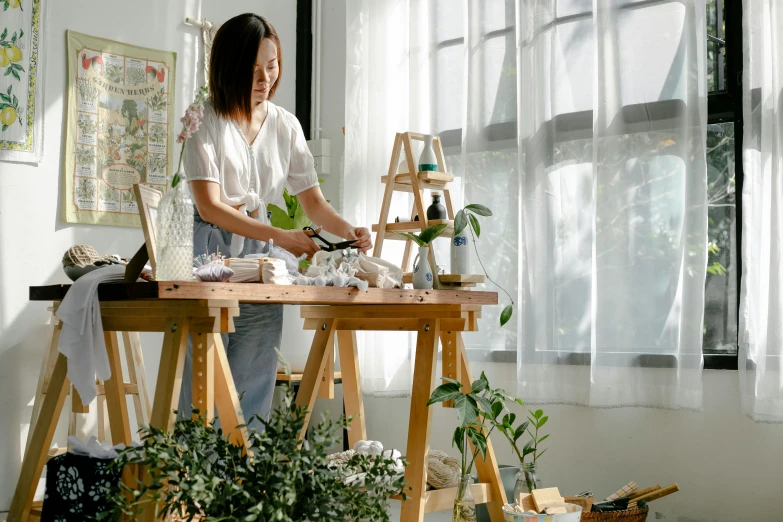 a woman that is standing in front of a table, inspired by Kim Du-ryang, pexels contest winner, crafting, gardening, architect studio, standing on a desk