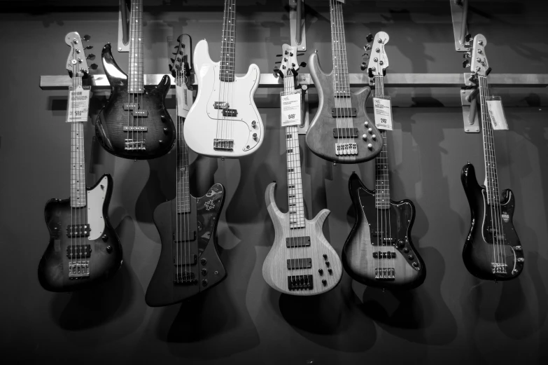 a bunch of guitars hanging on a wall, a black and white photo, by Dennis Flanders, pexels, precisionism, bass sound waves on circuitry, on display, vaughan bass, black white pink