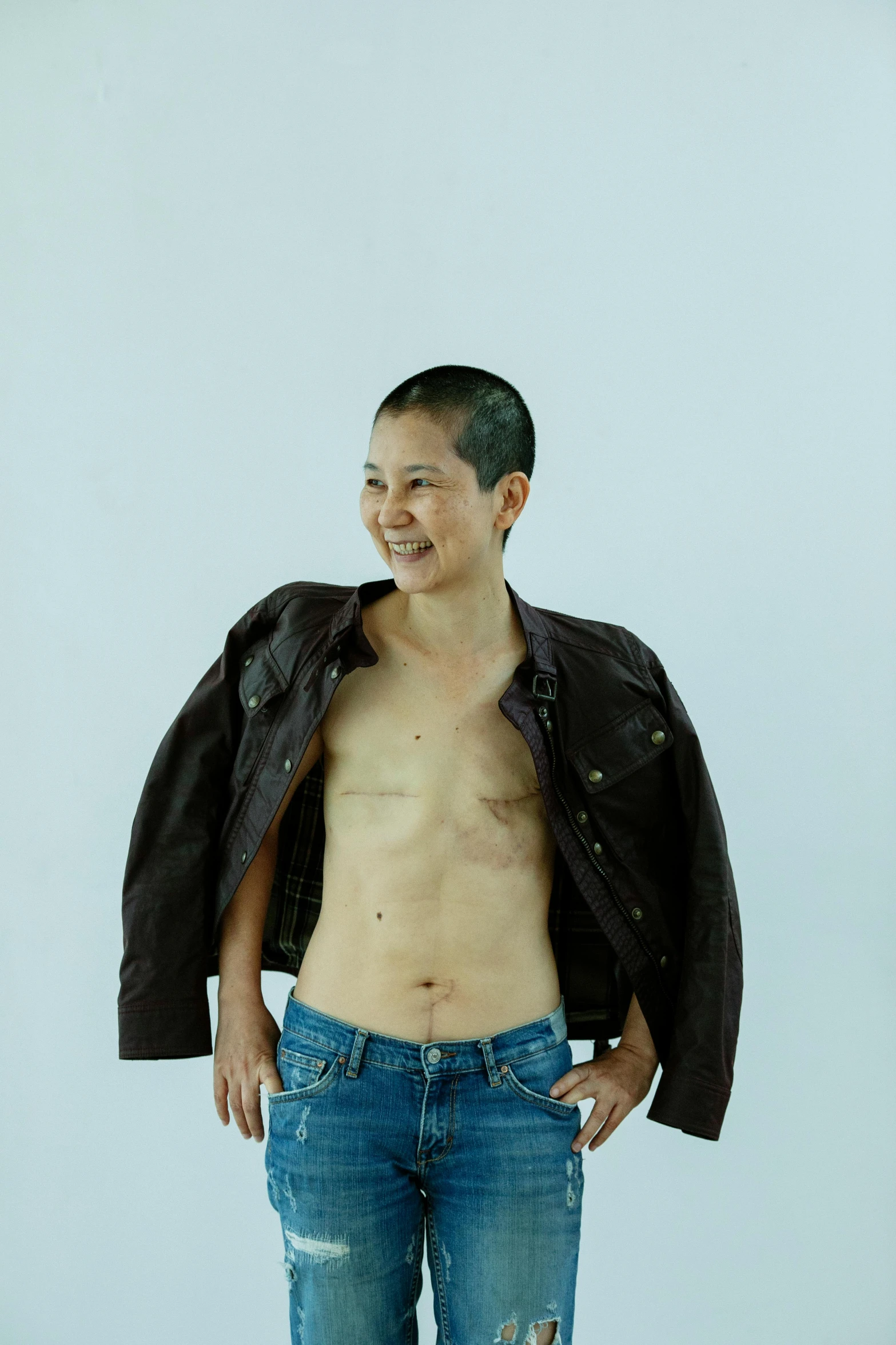 a man standing with his hands in his pockets, an album cover, inspired by Zhang Kechun, hyperrealism, an epic non - binary model, leather jacket and denim jeans, sie boob, taken in the early 2020s