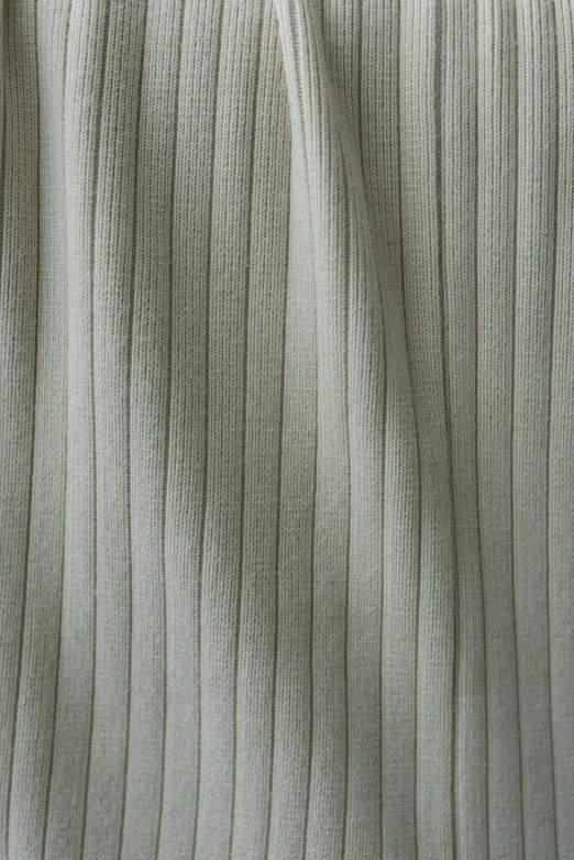 a white blanket sitting on top of a bed, corduroy, muted green, medium closeup, cotton fabric