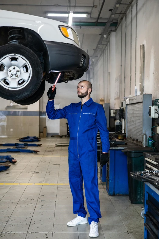 a mechanic working on a vehicle in a garage, blue tunic and robes, large tall, thumbnail, full height