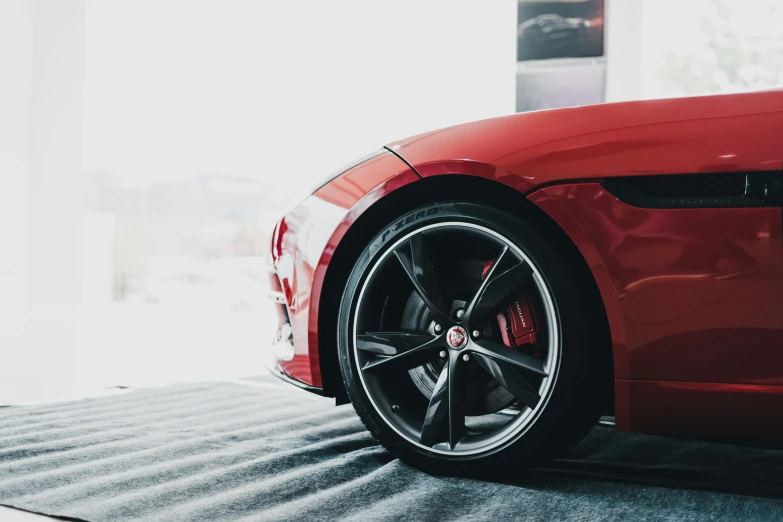 a red sports car parked in a showroom, pexels contest winner, tyre mark, jaguar, instagram post, detailed high resolution