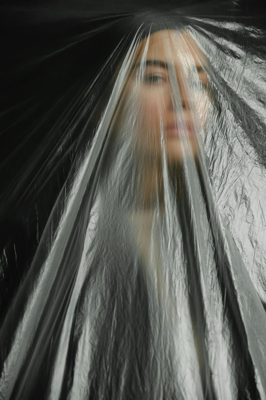 a close up of a person wrapped in plastic, an album cover, inspired by Anna Füssli, unsplash, dark drapery, vietnamese woman, photographed for reuters, pareidolia