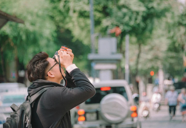 a man taking a picture of a street with a camera, pexels contest winner, goggles on forehead, 🚿🗝📝, darren quach, looking like a bird