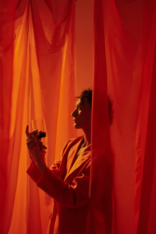 a man standing in front of a red curtain, inspired by Georges de La Tour, pexels contest winner, magic realism, colors orange, maya deren, smoking woman, person made out of glass