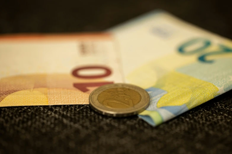 a coin sitting on top of a pile of money, by Daniel Lieske, pexels contest winner, renaissance, zoomed view of a banknote, textiles, promo image, taken with sony alpha 9