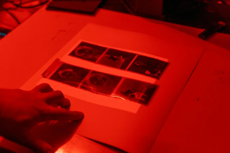 a person typing on a computer keyboard under a red light, flickr, holography, inking etching screen print, a seance, 33mm photo, with glow on some of its parts