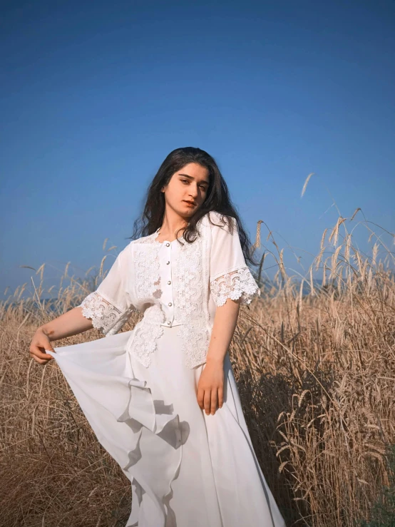 a woman standing in a field of tall grass, an album cover, by Marshall Arisman, unsplash, renaissance, pale-skinned persian girl, wearing a white folkdrakt dress, instagram story, wearing off - white style