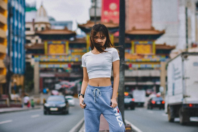 a woman standing in the middle of a city street, inspired by Wen Jia, trending on pexels, graffiti, croptop, philippines, pants, federation clothing