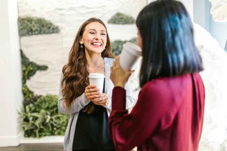 a woman standing next to a woman holding a cup of coffee, trending on pexels, happening, avatar image, welcoming smile, background image, aussie baristas