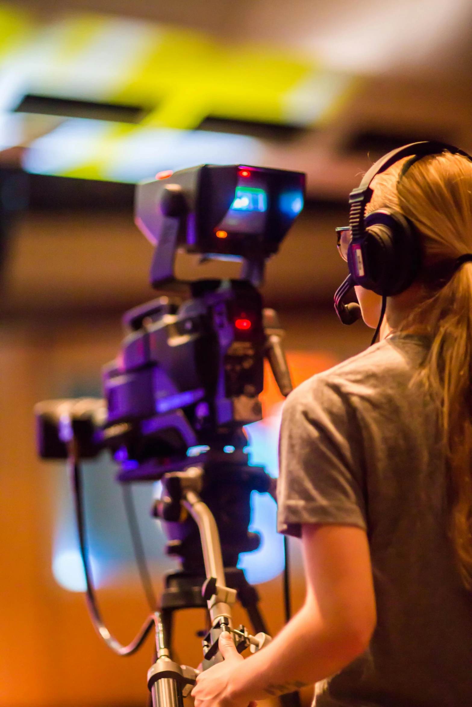 a woman standing in front of a video camera, shutterstock, girl wearing headphones, theatre equipment, from the back, high resolution photo