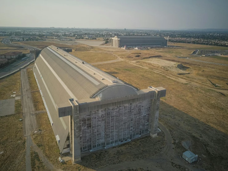 a large building sitting in the middle of a field, by Jeffrey Smith, unsplash, brutalism, united states air force, dieselpunk volgograd, refrigerated storage facility, high - angle view