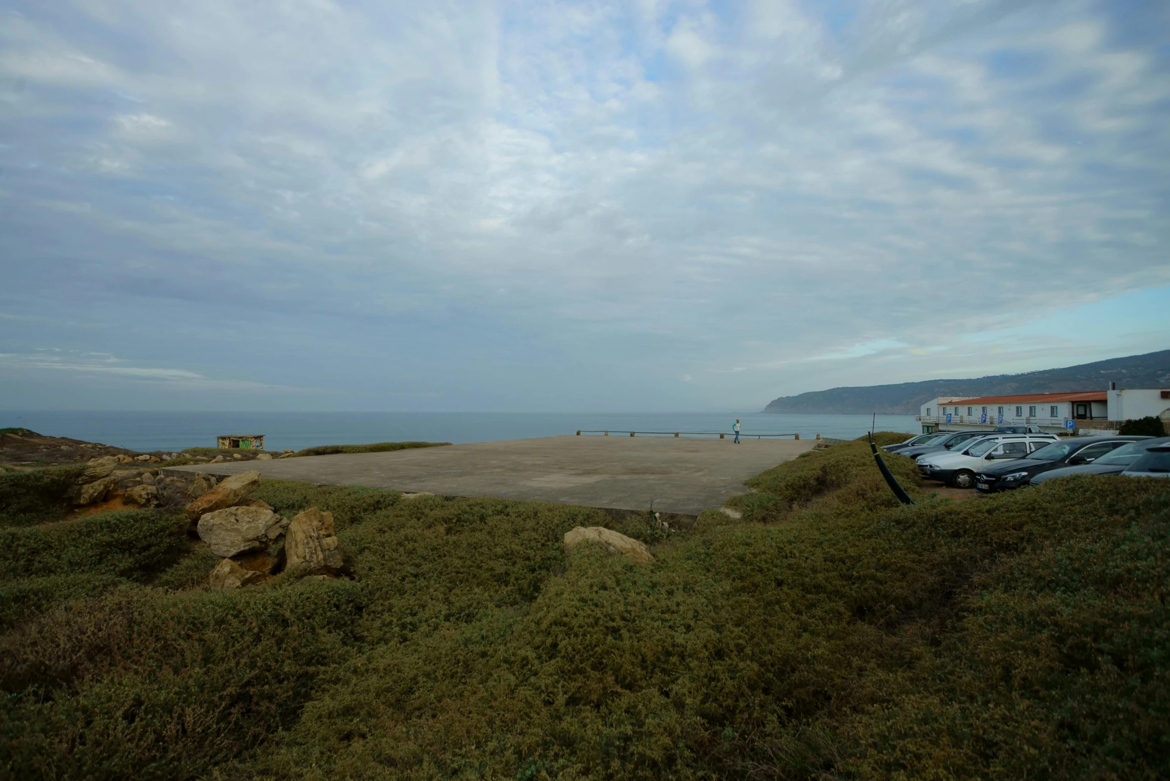 a parking lot next to the ocean on a cloudy day, a picture, les nabis, gigantic landing pad, views to the ocean, next to the sea, looking partly to the left