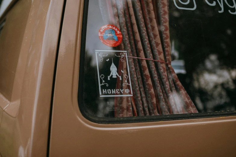 a close up of a car window with a sticker on it, by Emma Andijewska, pexels contest winner, wearing honey, hindu aesthetic, microbus, shot on sony a 7