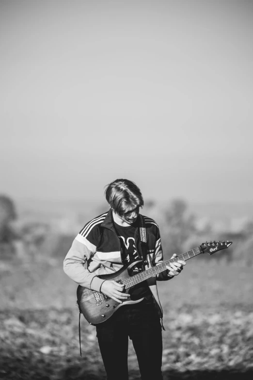 a black and white photo of a man playing a guitar, by Sebastian Spreng, on a hill, high quality picture, mr beast, dasha taran