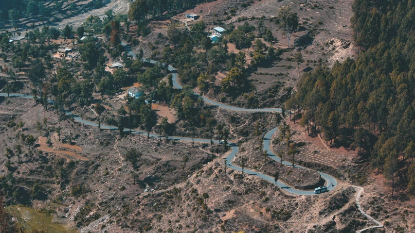 an aerial view of a winding road in the mountains, a tilt shift photo, pexels contest winner, hurufiyya, uttarakhand, thumbnail, houses and roads, arid mountains and palm forest